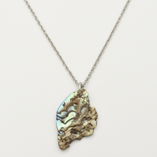 The "Necklace | Paua Shell Mahaki" by Salty Dreamers features a silver chain with an iridescent, naturally textured pāua shell pendant—ideal for adding effortless surfer style with its unique multicolored hues.