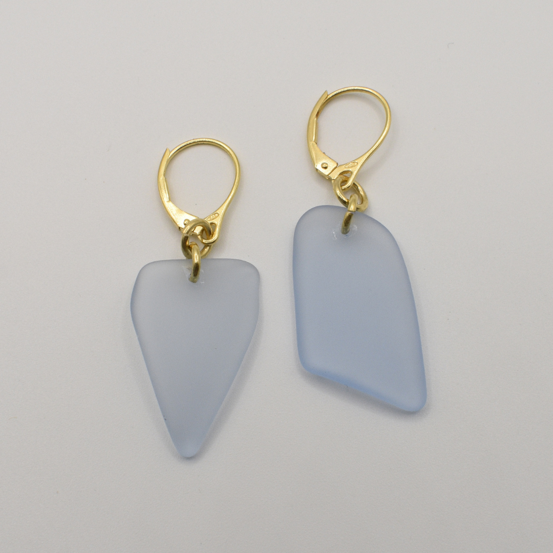 Salty Dreamers' Earrings | Seaglass Blue-Sky feature matte pale blue, irregular seaglass pendants on gold lever-back hooks, shown against a plain white background.