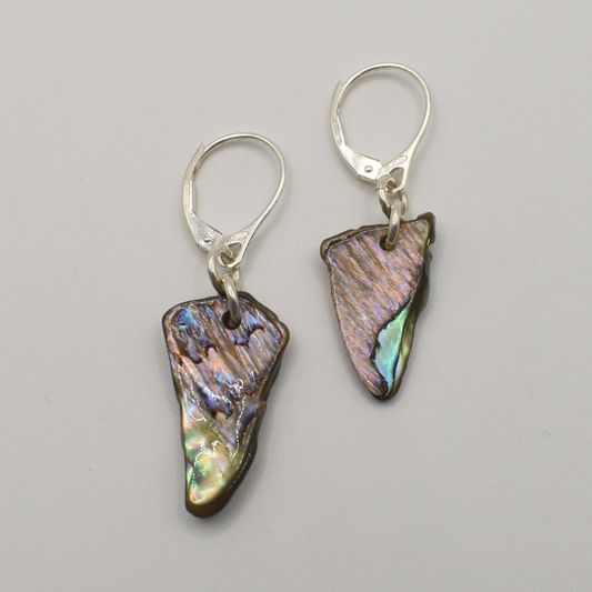 Salty Dreamers' Earrings | Paua Shell Tai feature handmade, irregularly shaped iridescent pāua shell pendants on 925 silver hooks, showcased against a plain light gray background.