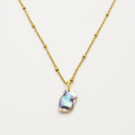 The Salty Dreamers Necklace | Paua Shell Ra features a golden stainless steel beaded chain and an iridescent, irregularly shaped paua shell pendant, shown centered against a plain white background.