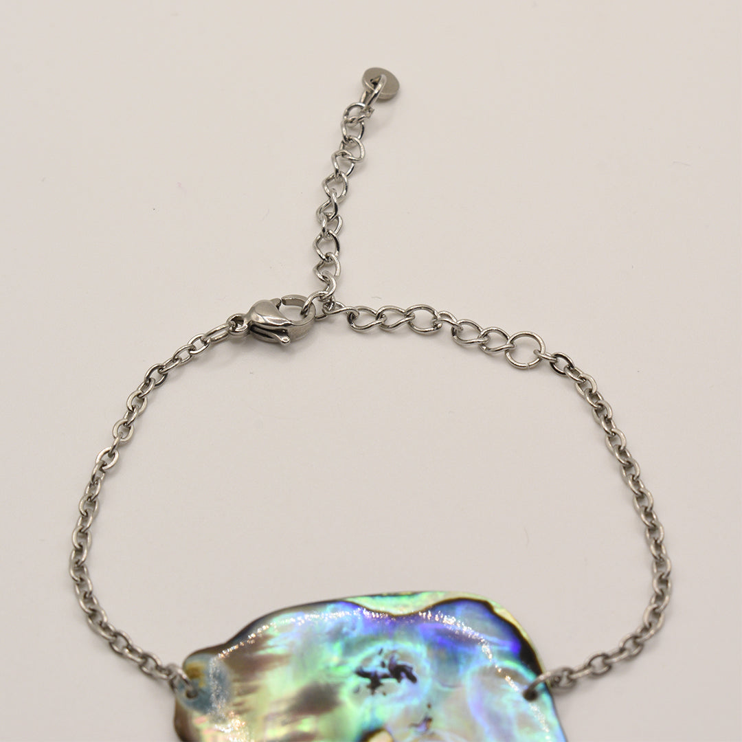 The Bracelet | Paua Shell Taurima by Salty Dreamers features a handmade pāua shell centerpiece on a silver stainless steel chain. This adjustable New Zealand piece is showcased on a plain white background, celebrating local craftsmanship.