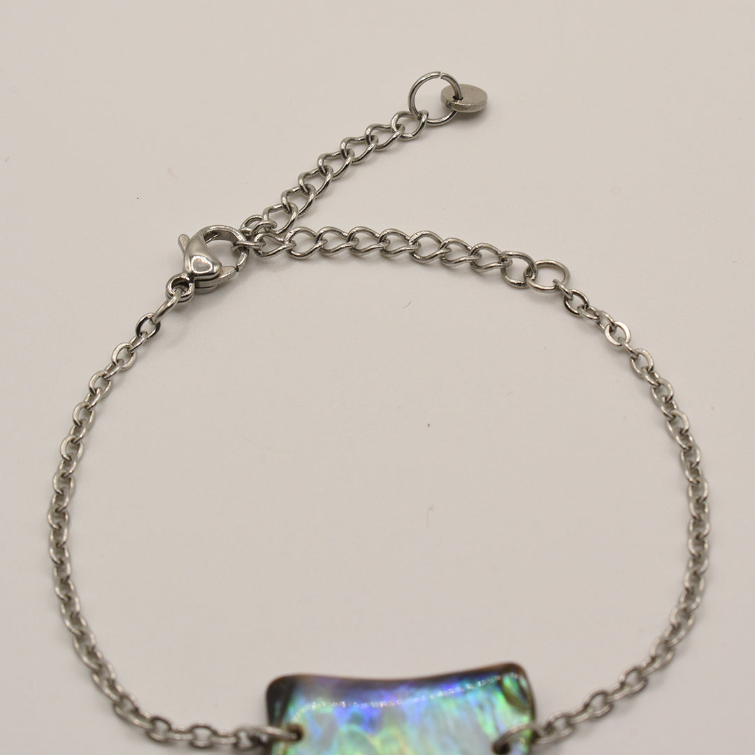 The Salty Dreamers Bracelet | Paua Shell Atarau is a handmade silver chain bracelet with an iridescent rectangular pāua shell charm, lobster clasp, and adjustable extension, shown on a plain white background.