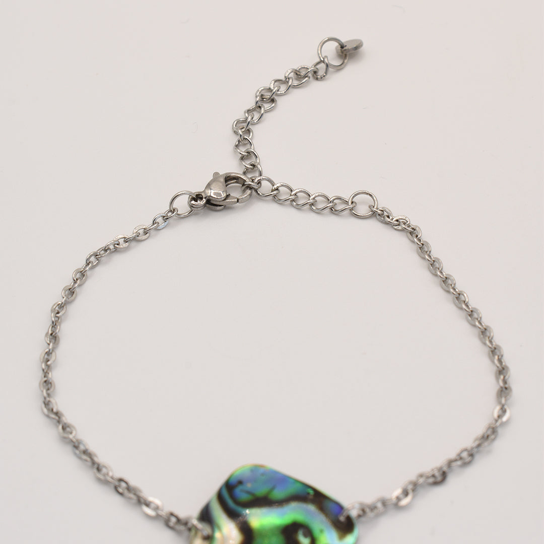 The Salty Dreamers Bracelet | Paua Shell Tai features a delicate silver chain, adjustable clasp, and vibrant pāua shell centerpiece. This handmade ocean-inspired jewelry piece is displayed on a plain white background.