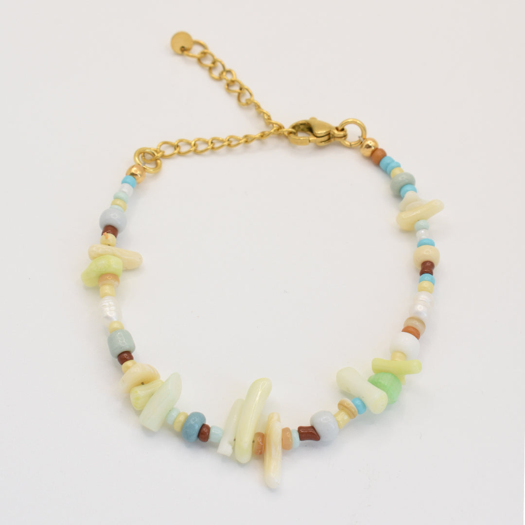 The Salty Dreamers Bracelet | Ocean Bamboo Rainbow features a gold chain with multicolored irregular handmade beads and small round beads in pastel green, blue, brown, and white for a casual, natural look.