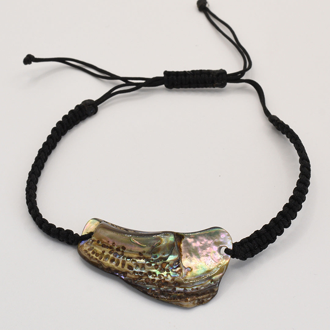 The Salty Dreamers Bracelet | Paua Shell Ngakau is a handmade black braided cord bracelet with an irregular, iridescent New Zealand paua shell centerpiece and an adjustable sliding knot closure.