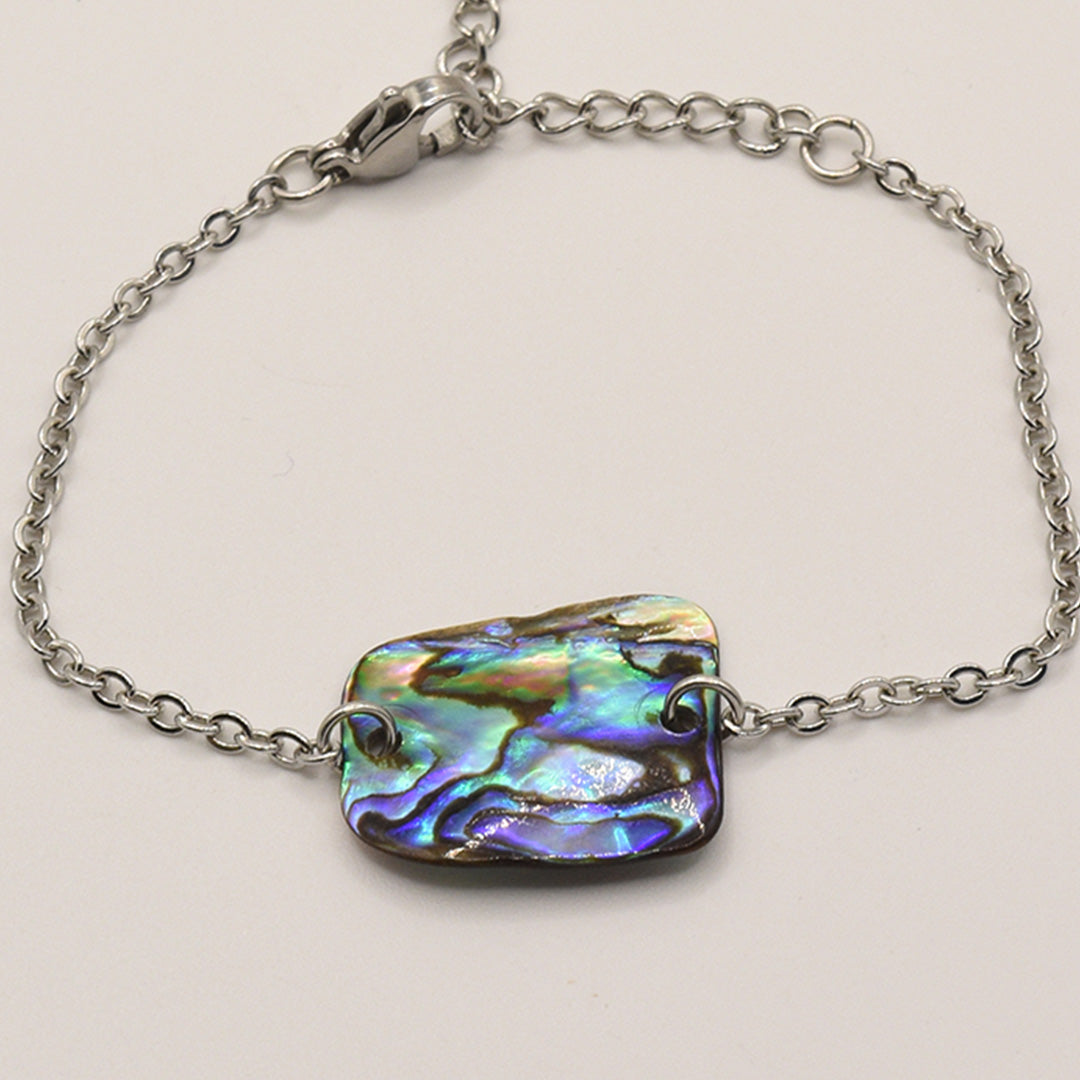 The Bracelet | Paua Shell Marama by Salty Dreamers is a handmade silver chain bracelet with a rectangular, iridescent pāua shell centerpiece showcasing swirling blue, green, and purple tones—a beautiful piece of New Zealand jewelry.