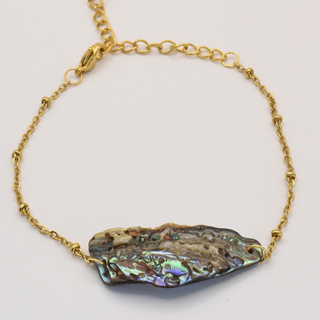 Salty Dreamers Bracelet | Paua Shell Takaro features a gold chain and a striking, iridescent paua shell centerpiece with natural purple, green, and blue hues—an exquisite piece of handmade New Zealand jewelry.