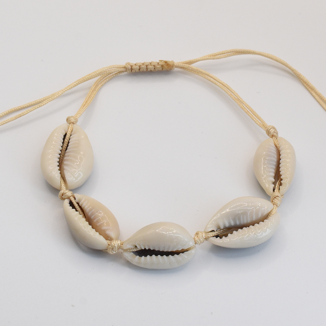 The Salty Dreamers Bracelet | Cowrie Away Beige features five white cowrie shells evenly spaced on a beige macramé cord, shown against a white background.
