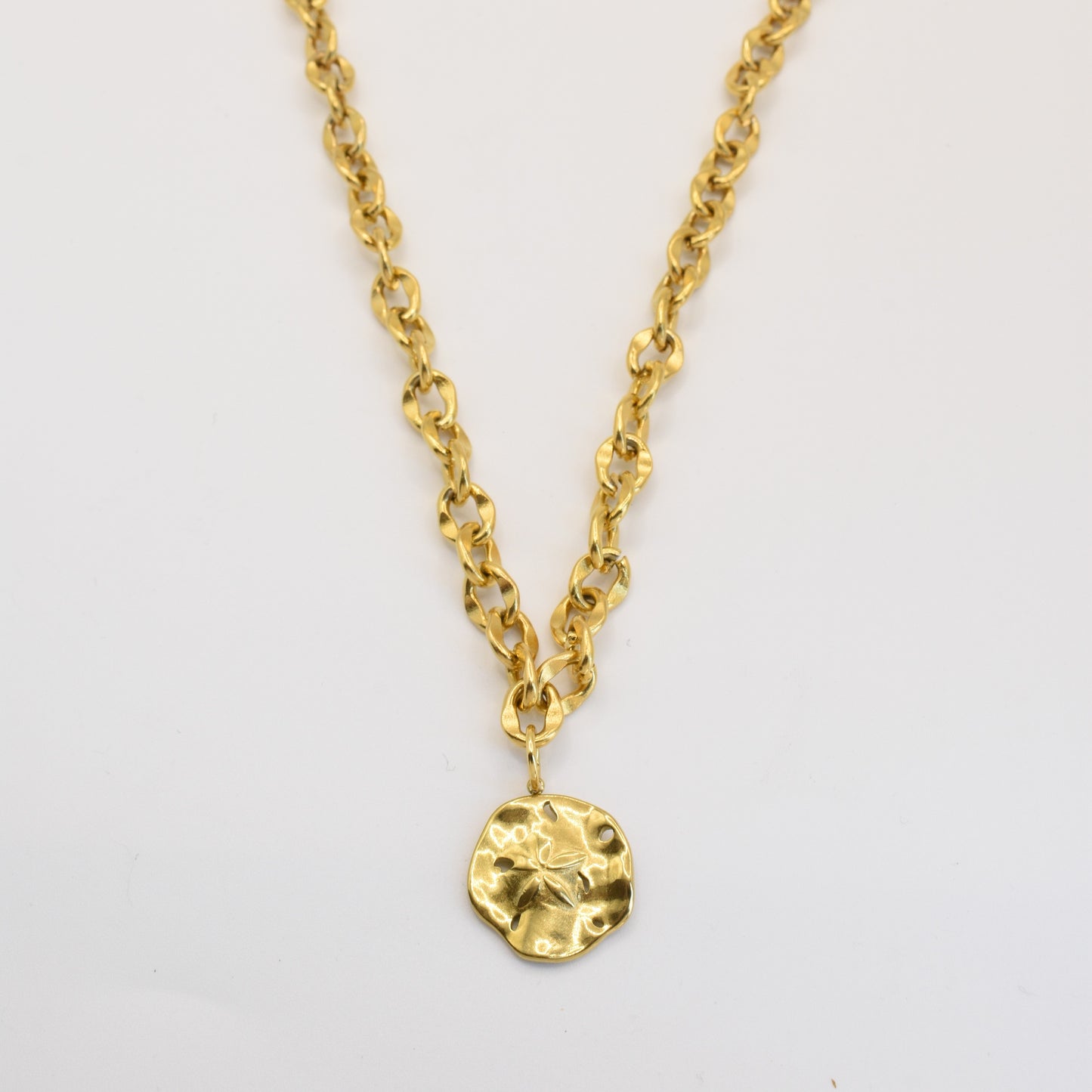 The Salty Dreamers Necklace | Ocean Dollar Gold features large gold links and a round, hammered pendant at the center. This handmade piece is showcased against a plain white background.