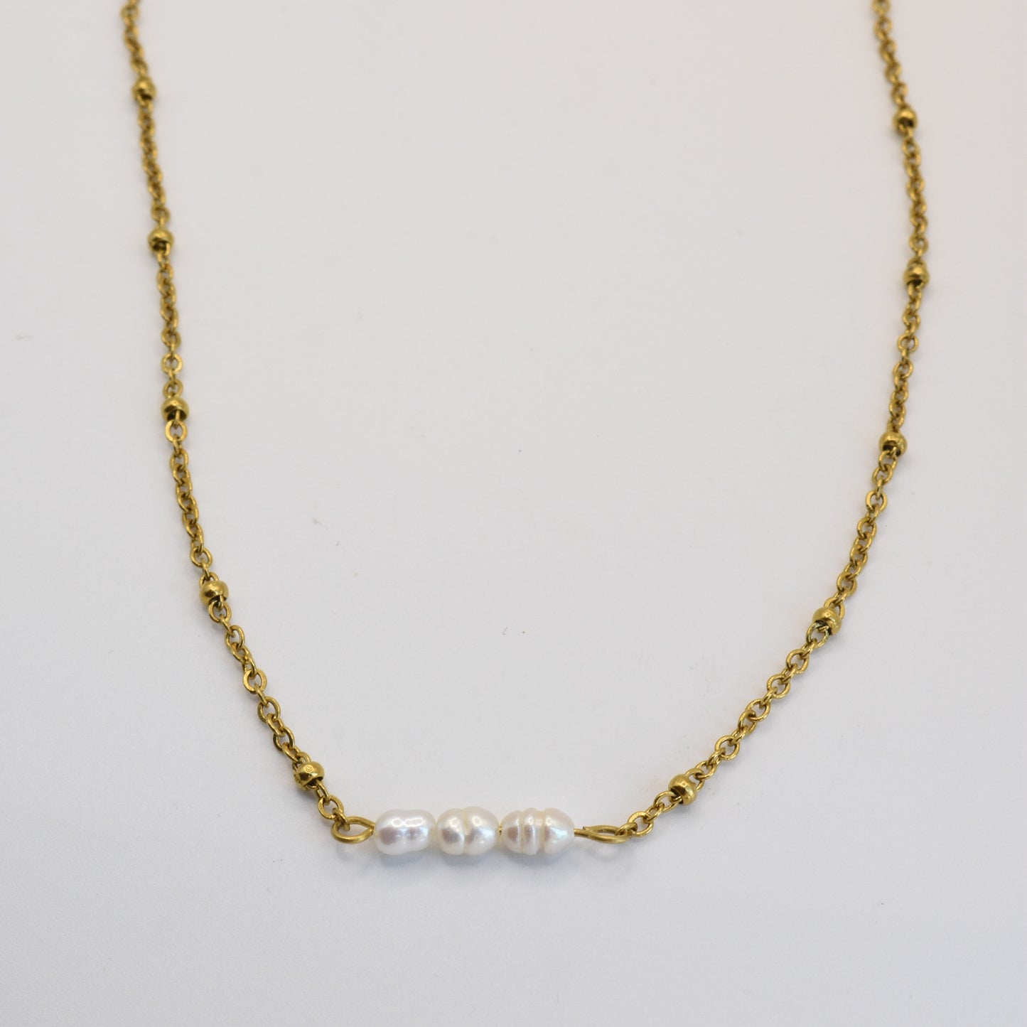 The Pretty Pearly Gold necklace by Salty Dreamers features a delicate gold chain with three small freshwater pearls in a row, shown on a plain white background.