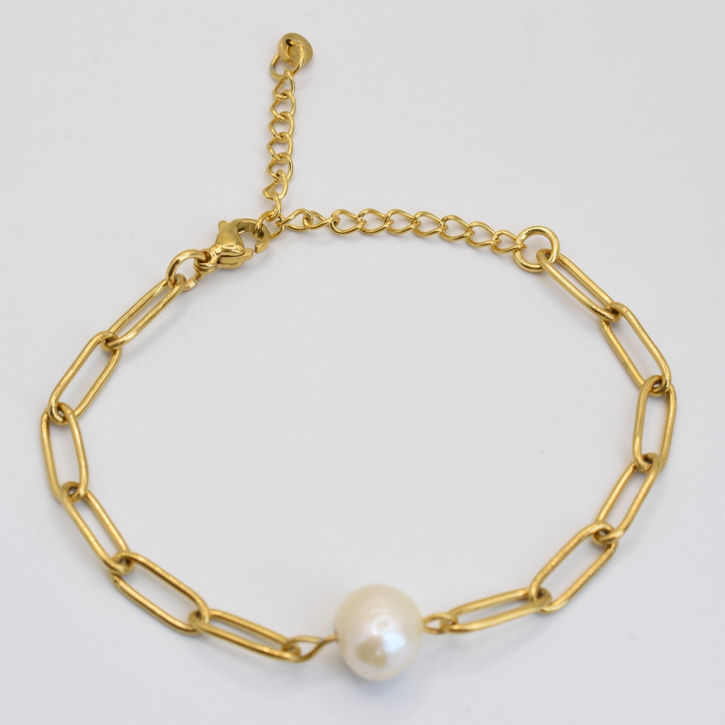 The Bracelet | Paperclip Cutie Gold by Salty Dreamers is a handmade gold chain with elongated links and a central freshwater pearl, featuring an adjustable clasp and shown on a white background.