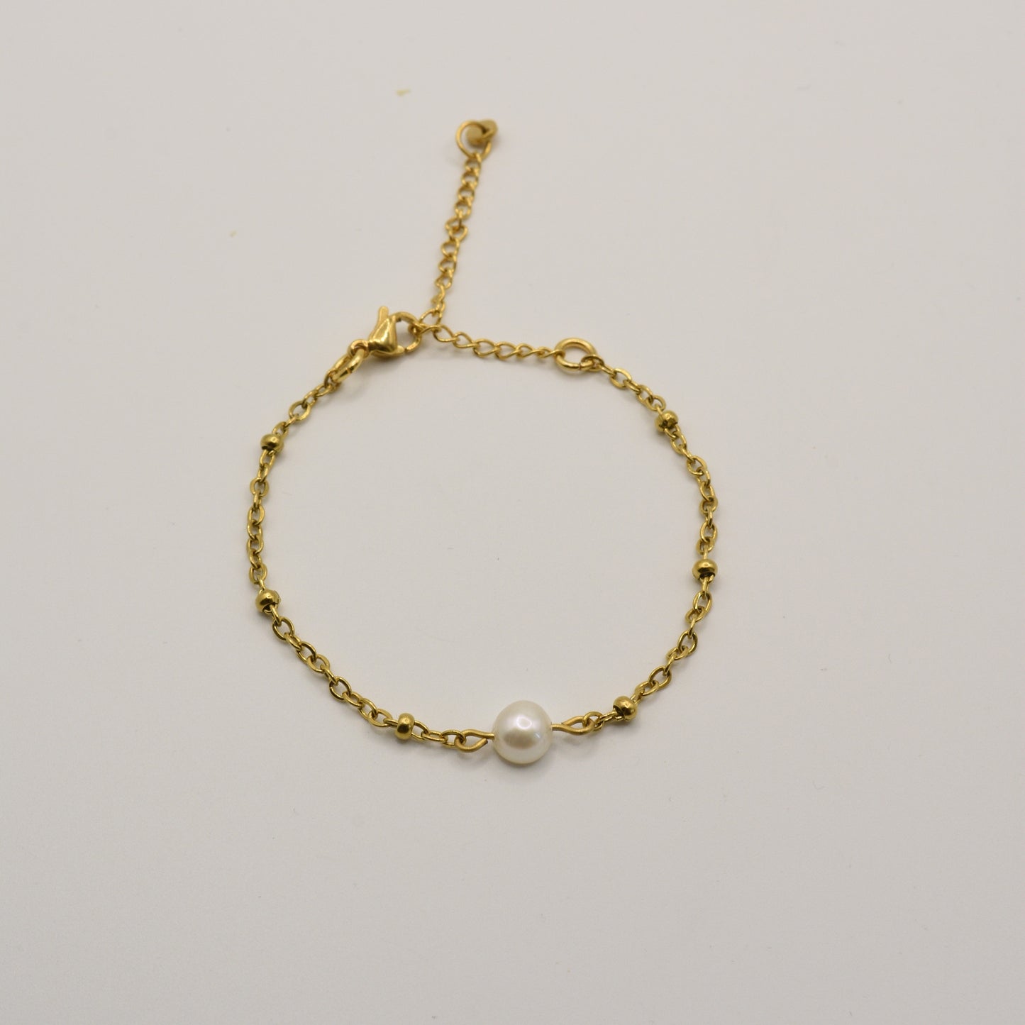 The Bracelet | Cutie Pearly Gold by Salty Dreamers features a delicate gold chain with small beads and a central white pearl, handmade for minimalist surfer style. Shown against a plain white background.