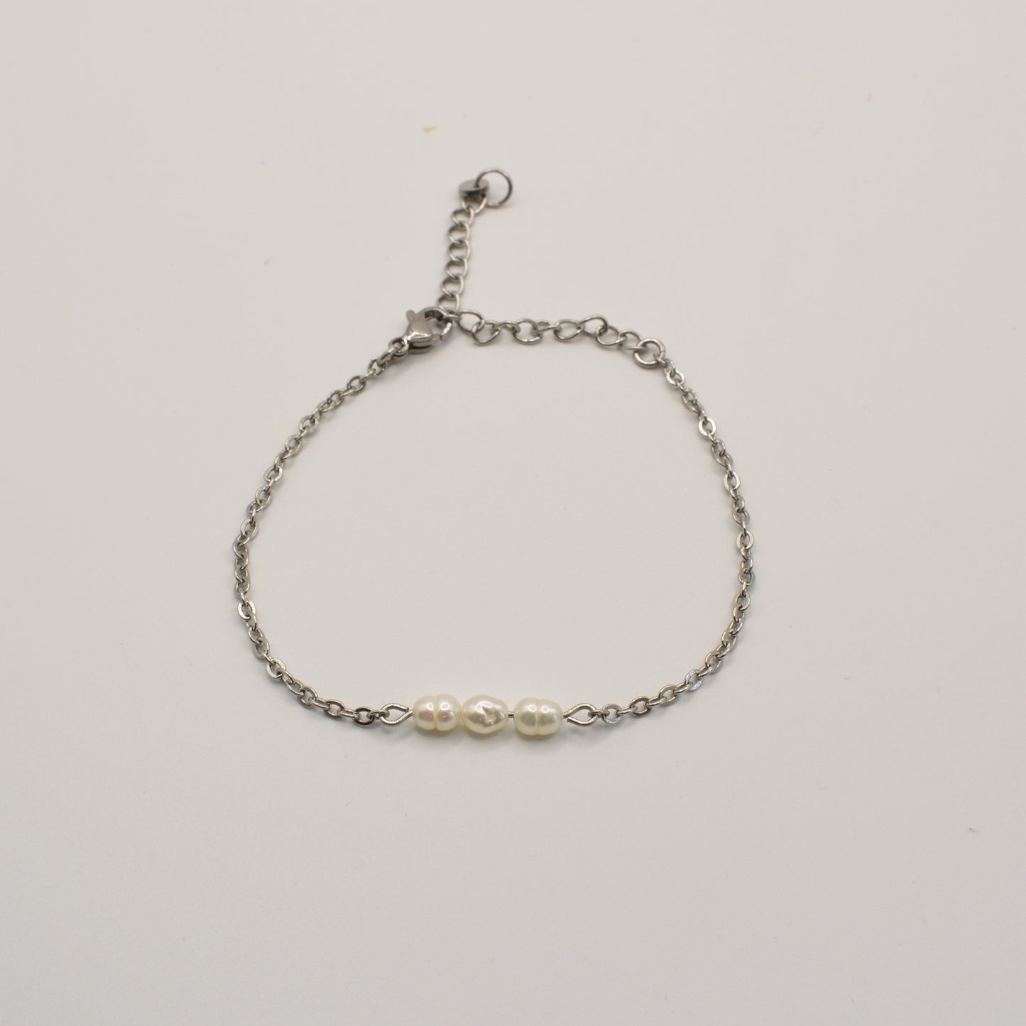 The Pretty Pearly Silver Bracelet by Salty Dreamers features a delicate silver chain and three small white pearls at the center, shown against a plain white background.