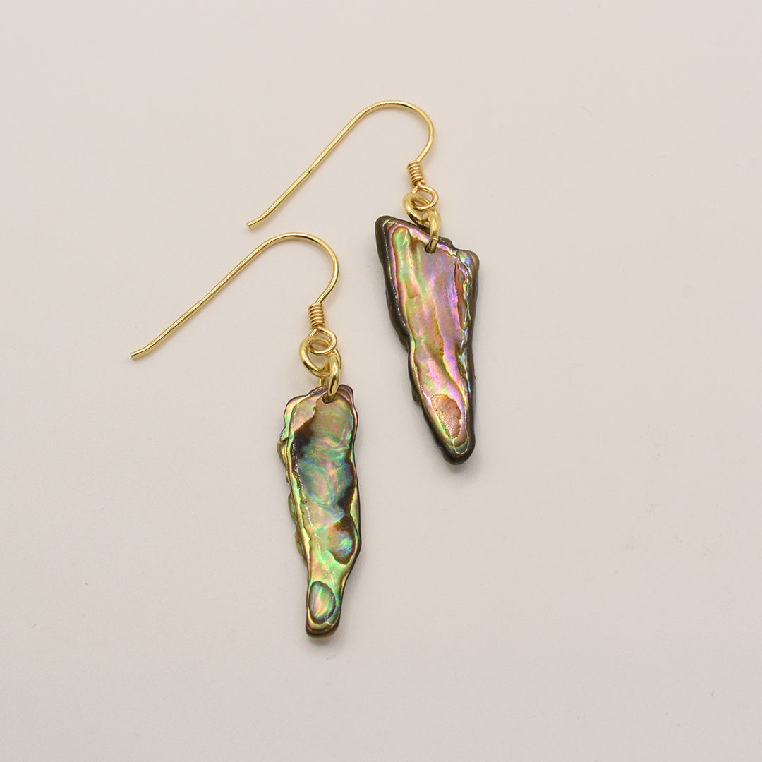 Salty Dreamers’ Paua Shell Mahaki earrings feature irregular, elongated New Zealand abalone pendants in iridescent green, pink, and gold tones, each hanging from a simple gold-plated silver hook.