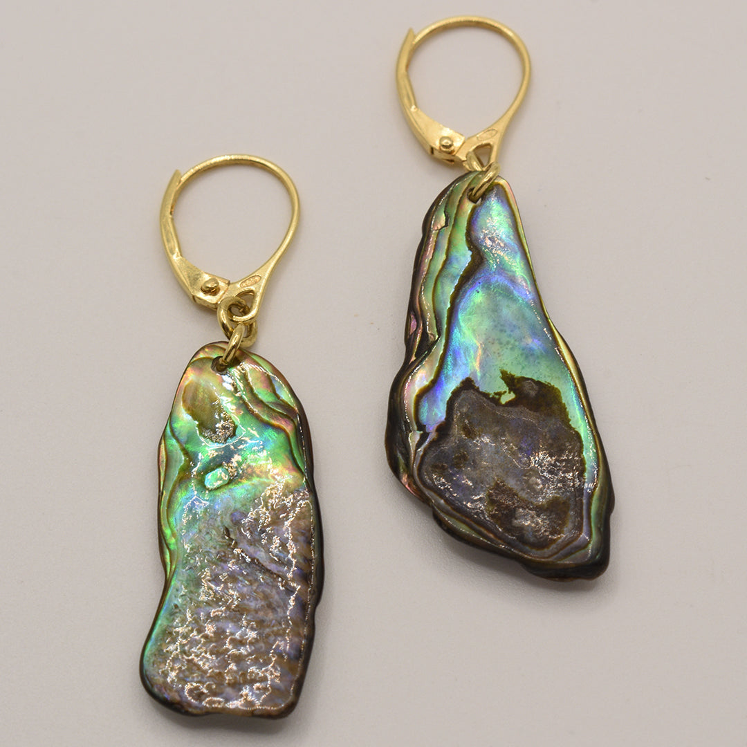 Salty Dreamers Paua Shell Marie Earrings are gold-plated silver leverbacks with irregular paua shell pendants, displaying iridescent green, blue, and purple hues on a light background.