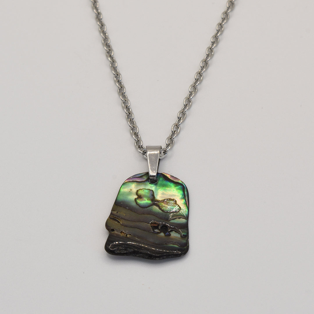 The Salty Dreamers Necklace | Paua Shell Kowhai features a handmade silver chain with an iridescent pāua shell pendant in green, blue, and brown tones, shown on a plain white background.