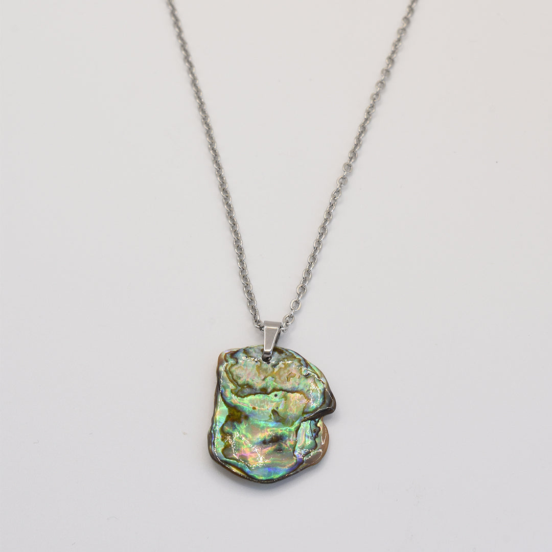 The Necklace | Paua Shell Kaukau by Salty Dreamers features an iridescent, irregular pāua shell pendant on a silver chain—a handmade piece that showcases natural beauty, displayed on a plain white background.