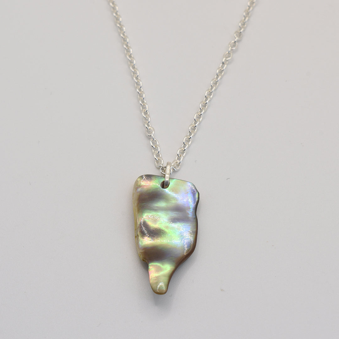 The Salty Dreamers Necklace | Paua Shell Ruru features a handmade sterling silver chain with an irregular, iridescent abalone shell pendant, perfect for ocean jewelry lovers. Shown on a plain white background.
