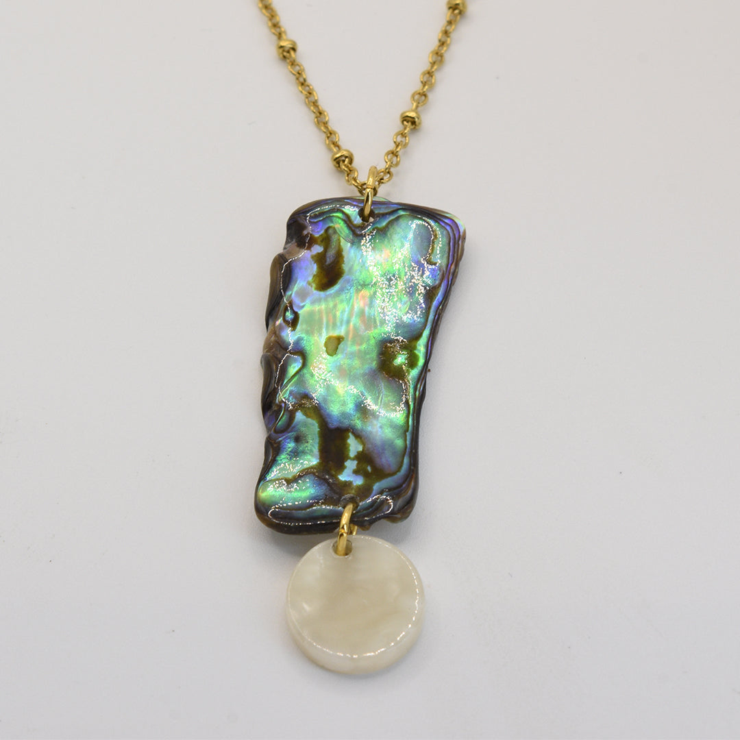 The Salty Dreamers Paua Shell Hine Necklace is a handmade gold chain featuring a rectangular New Zealand abalone shell pendant with a round white mother-of-pearl charm hanging below.