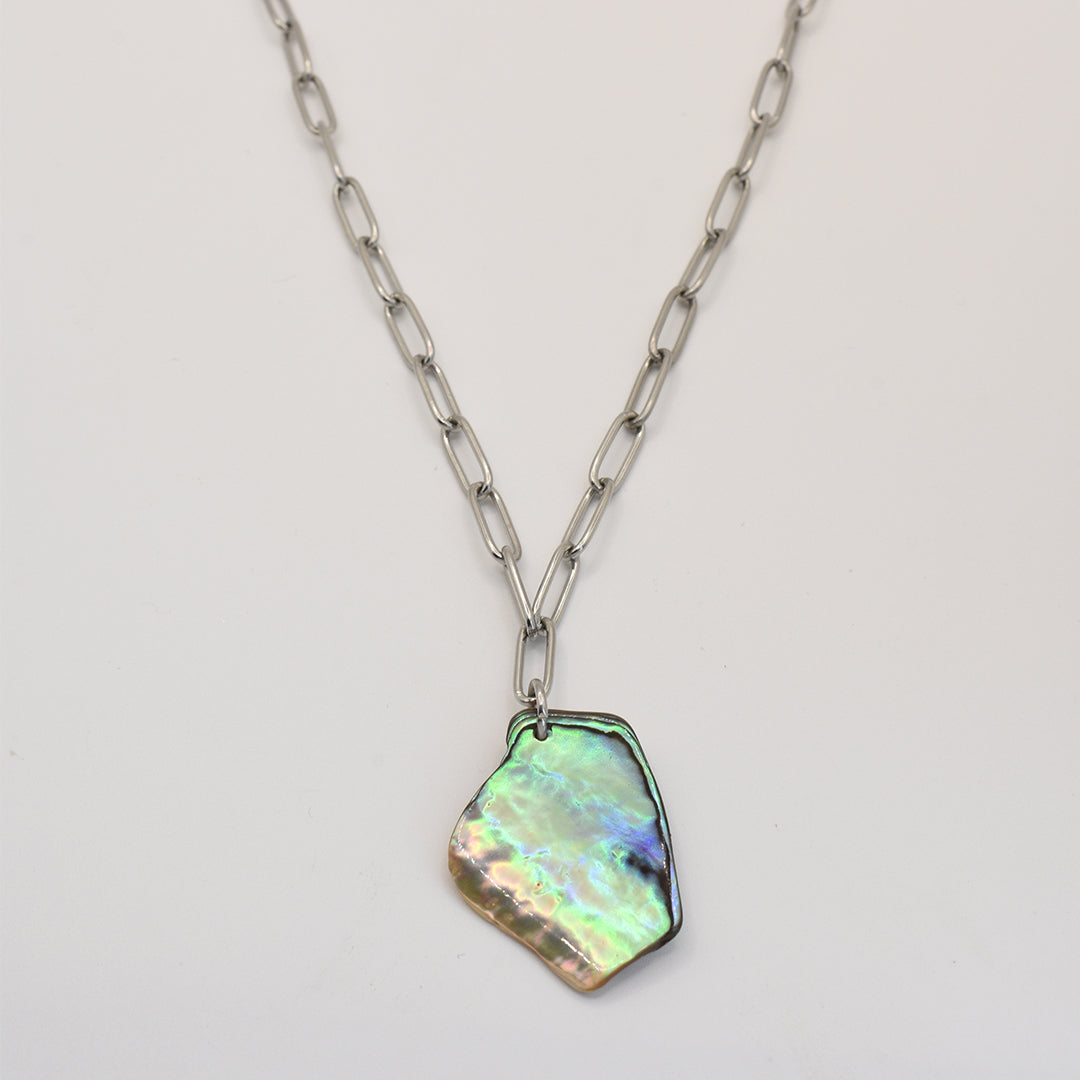 The Salty Dreamers Necklace | Paua Shell Koura features a chunky silver stainless steel link chain with an iridescent, irregular-shaped pāua shell pendant, shown against a plain white background.