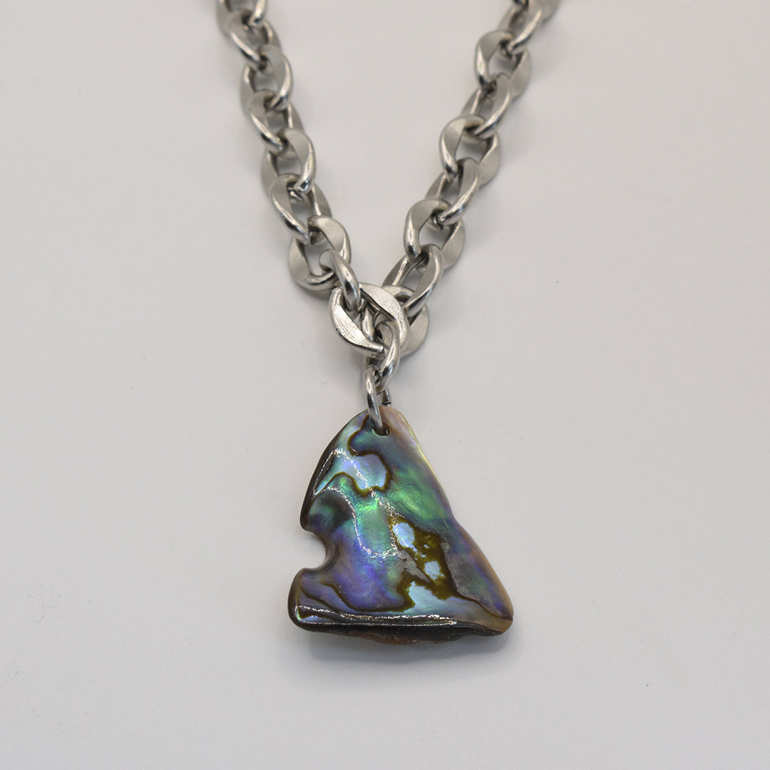 The Salty Dreamers Necklace | Paua Shell Waka features a chunky silver chain and an irregular, iridescent pāua shell pendant in greens, blues, and purples—perfect to pair with handmade New Zealand jewelry and pāua shell earrings.