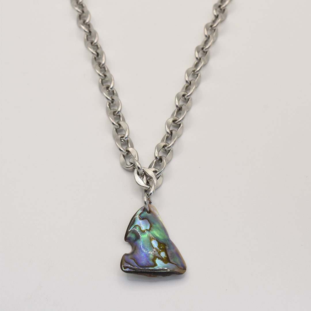 A silver chain necklace, the Necklace | Paua Shell Waka by Salty Dreamers, features an iridescent, arrowhead-shaped pendant handmade in New Zealand from paua shell, displayed on a plain white background.
