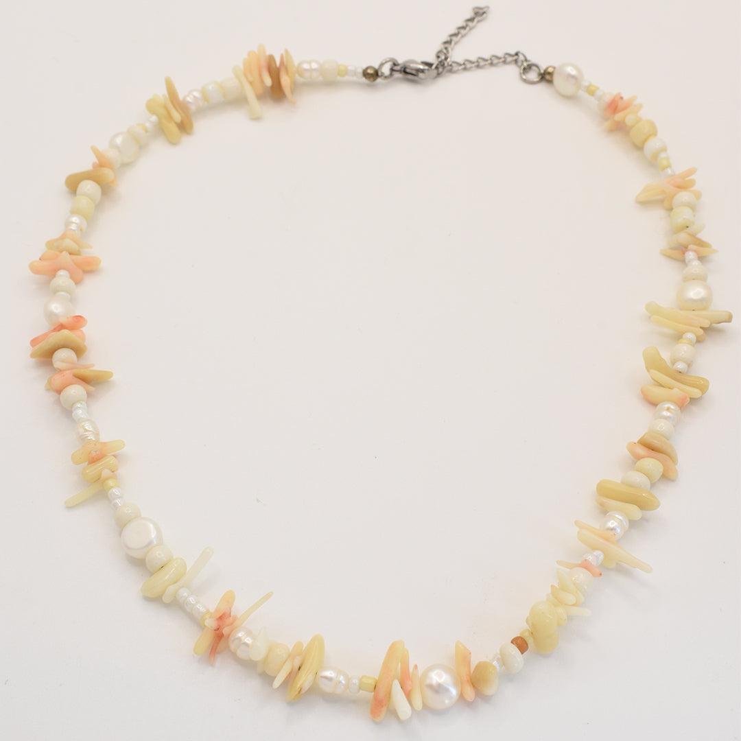 The Salty Dreamers Necklace | Ocean Bamboo Pink is a handmade piece featuring irregular cream and pale pink shell beads, small round white accents, and a silver adjustable chain clasp.
