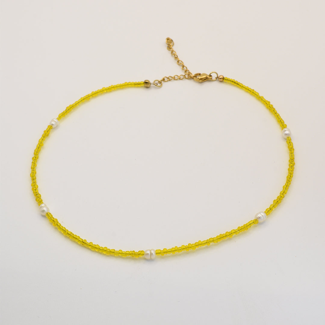 The Salty Dreamers Necklace | Starfish features delicate yellow beads, evenly spaced white pearls, and a gold adjustable clasp, all handmade in Germany and shown on a plain white background.