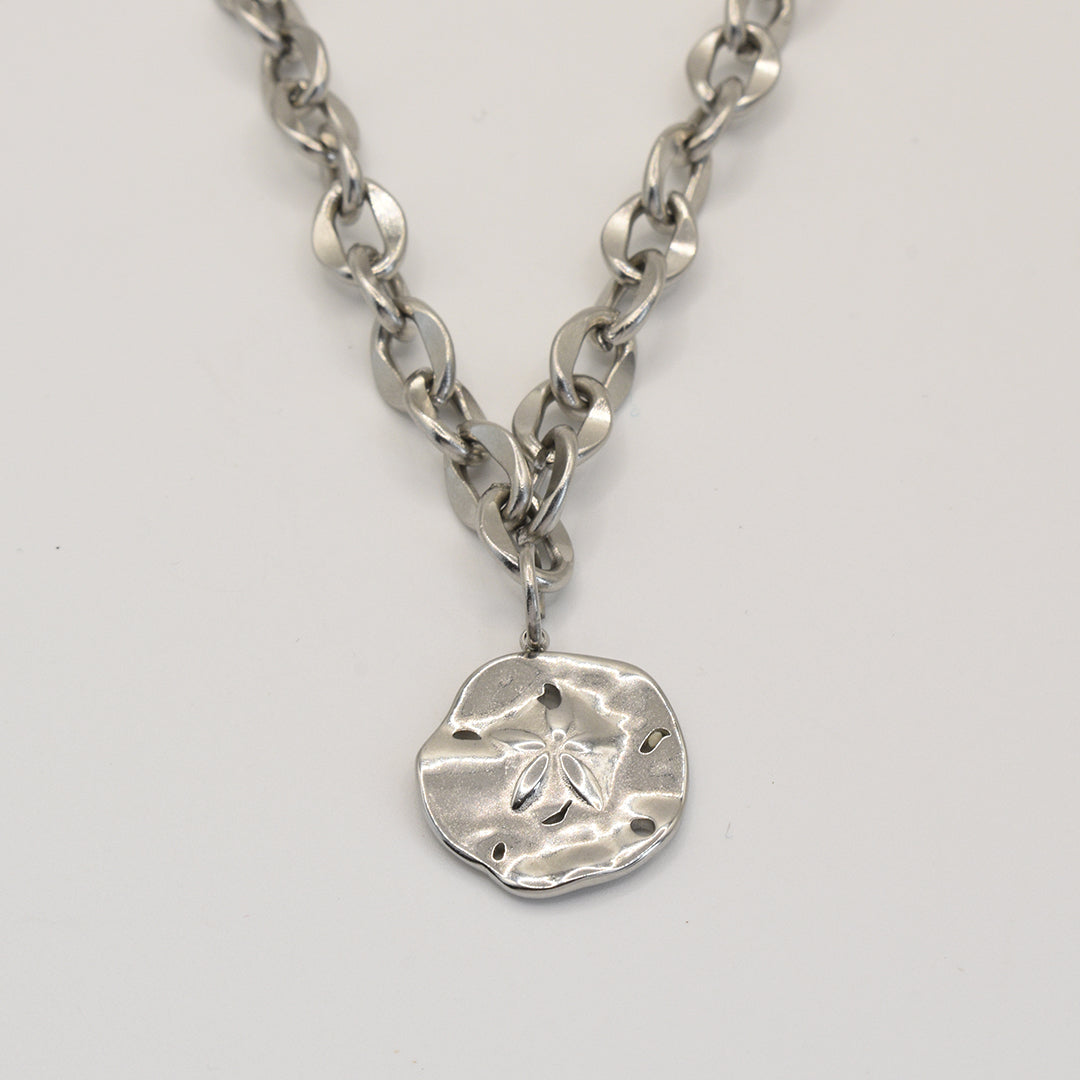 The Salty Dreamers Necklace | Ocean Dollar Silver features a chunky silver chain with a round, textured sand dollar pendant and cut-out details, shown on a plain light background.