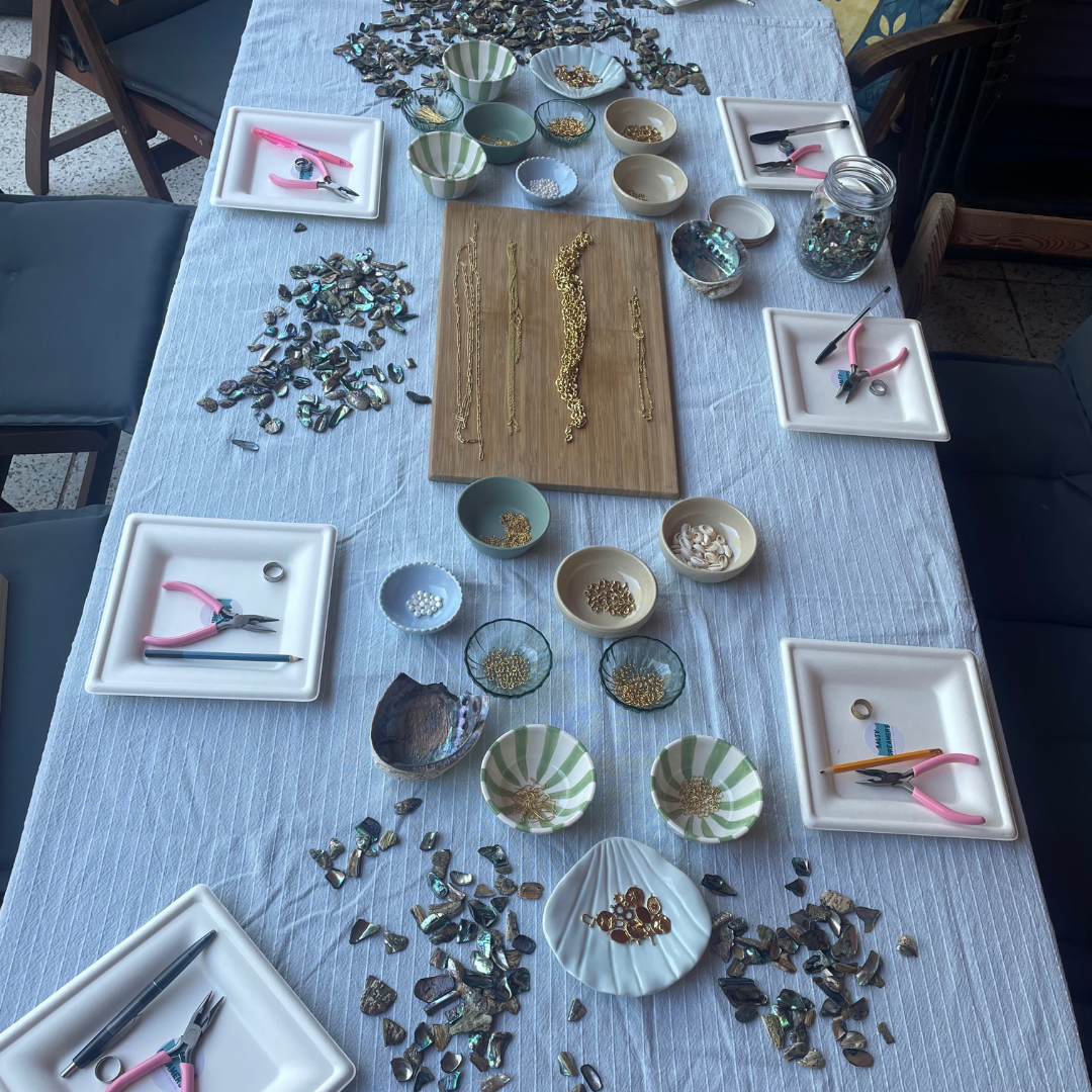Table with jewelry-making materials and tools on a blue tablecloth.