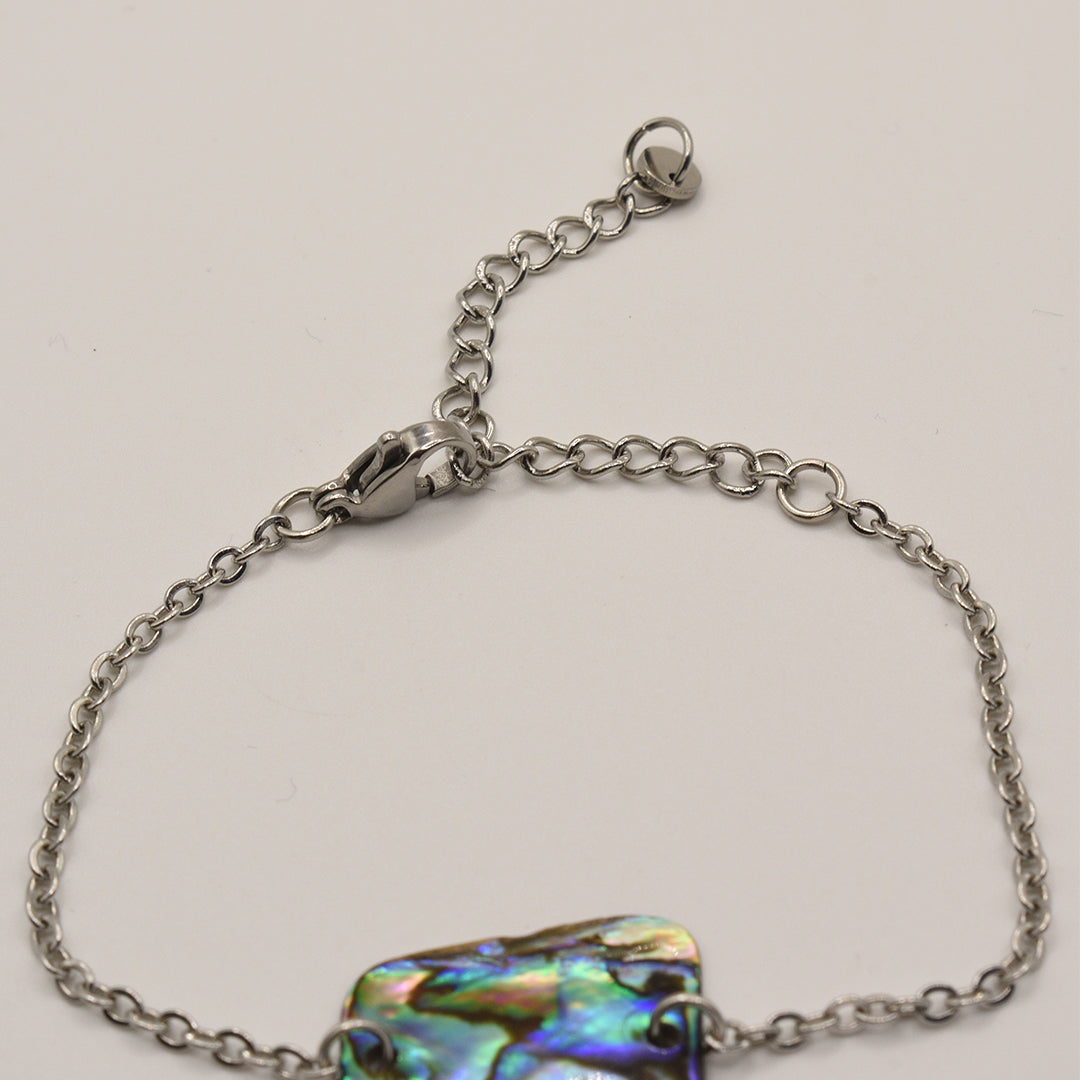 The Salty Dreamers Bracelet | Paua Shell Marama is a handmade silver chain bracelet with an iridescent abalone centerpiece, lobster clasp, and adjustable extender chain, shown on a plain white background.