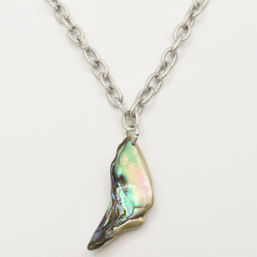 The Salty Dreamers Necklace | Paua Shell Hau features a handmade silver chain with a wing-shaped pendant, crafted from iridescent pāua shell in green, pink, and blue tones on a white background.