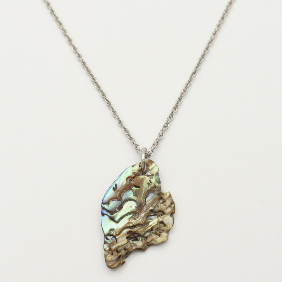 The "Necklace | Paua Shell Mahaki" by Salty Dreamers features a silver chain with an iridescent, naturally textured pāua shell pendant—ideal for adding effortless surfer style with its unique multicolored hues.