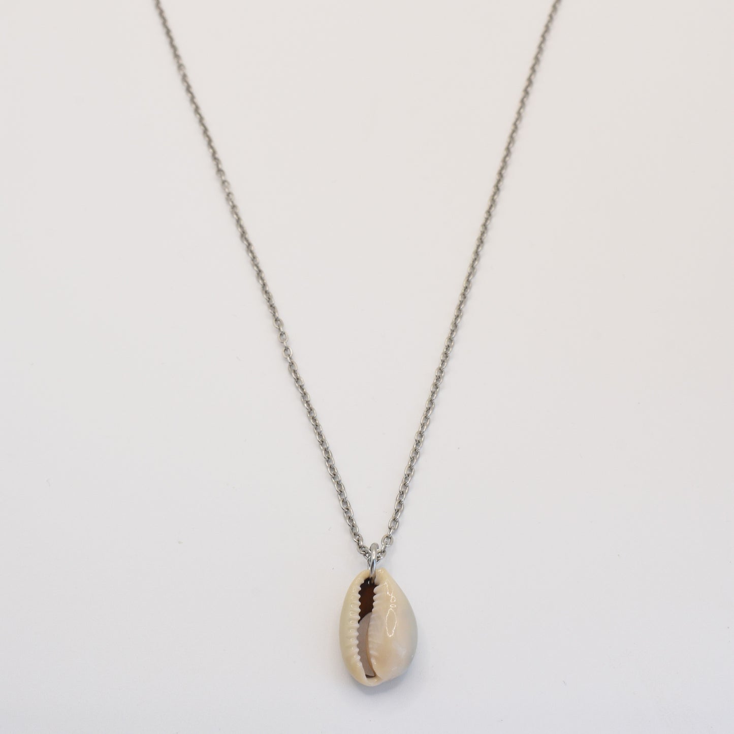 The Necklace | Simplified Cowrie Silver by Salty Dreamers features a handmade silver chain with a single cowrie pendant, beautifully displayed against a plain white background.