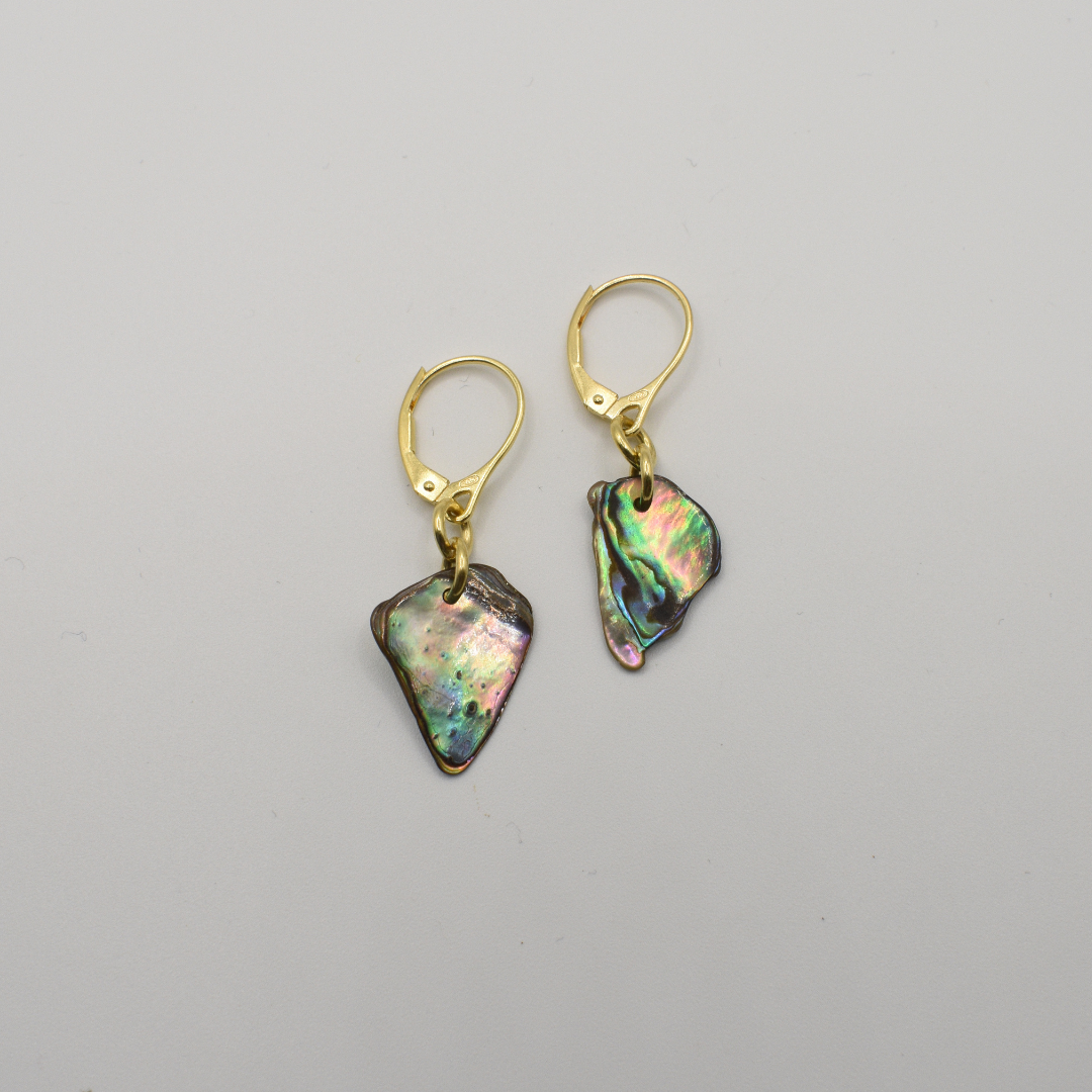 The Salty Dreamers Paua Shell Hihiri earrings feature handmade, irregularly shaped iridescent pendants and gold leverback hooks, shown against a plain white background.