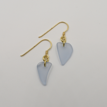 Salty Dreamers' Earrings | Seaglass Small Blue feature handmade, irregular triangle pendants made from translucent light blue seaglass and gold hooks, shown on a plain white background.