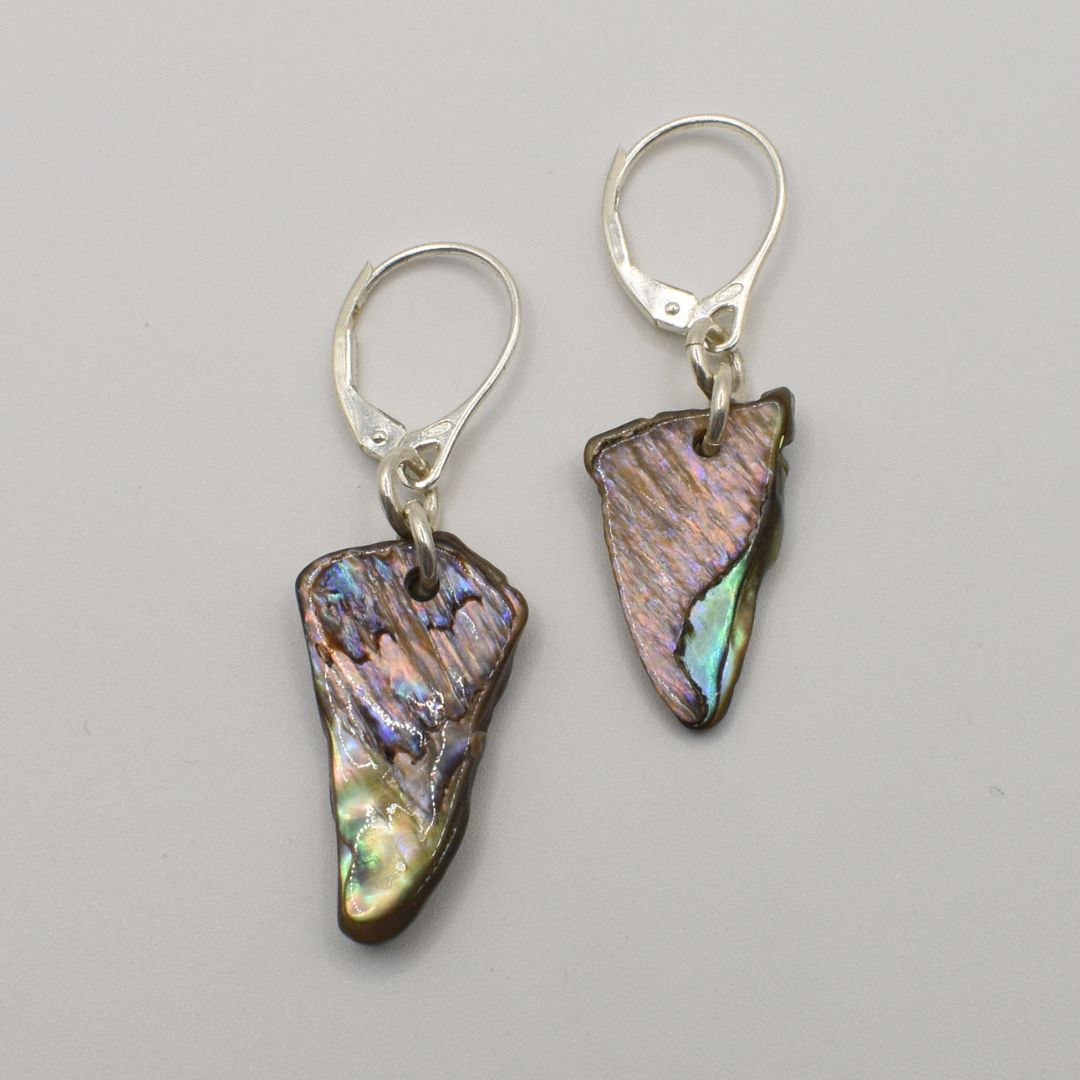 Salty Dreamers' Earrings | Paua Shell Tai feature handmade, irregularly shaped iridescent pāua shell pendants on 925 silver hooks, showcased against a plain light gray background.