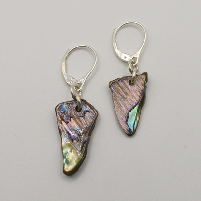Salty Dreamers' Earrings | Paua Shell Tai feature handmade, irregularly shaped iridescent pāua shell pendants on 925 silver hooks, showcased against a plain light gray background.