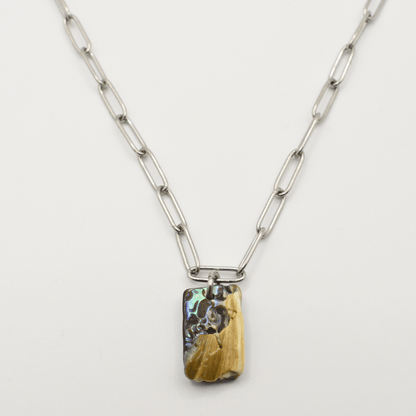 The Necklace | Paua Shell Ngaru by Salty Dreamers features large silver rectangular links and a vibrant paua shell pendant in yellow, brown, and blue tones. This handmade New Zealand piece is shown on a white background.