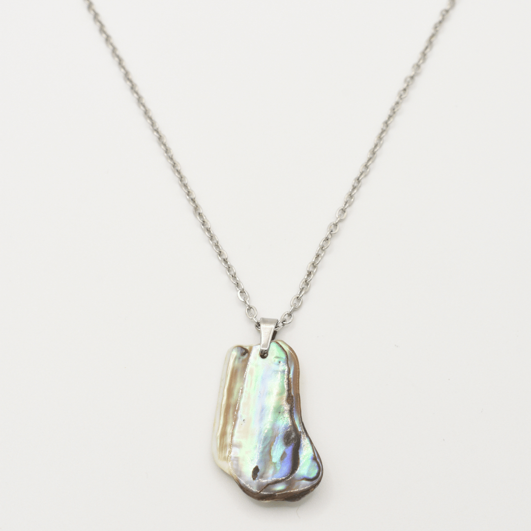 The Salty Dreamers Necklace | Paua Shell Kaukau features a handmade silver chain with an iridescent, uniquely-shaped paua shell pendant, shown on a white background.