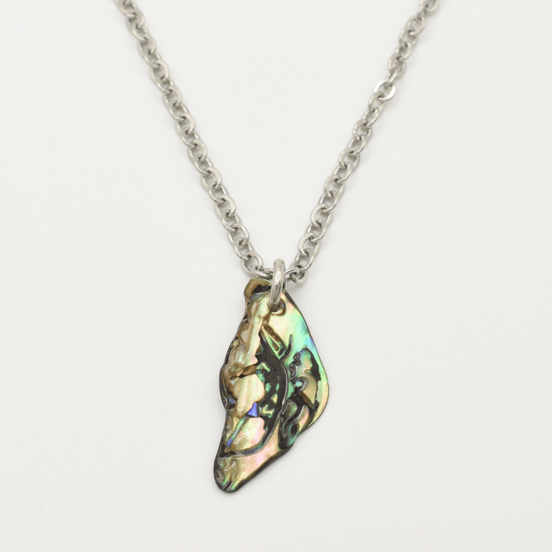 The Salty Dreamers Necklace | Paua Shell Takaro features a handmade silver chain with an irregular iridescent pāua shell pendant, displayed on a plain white background.