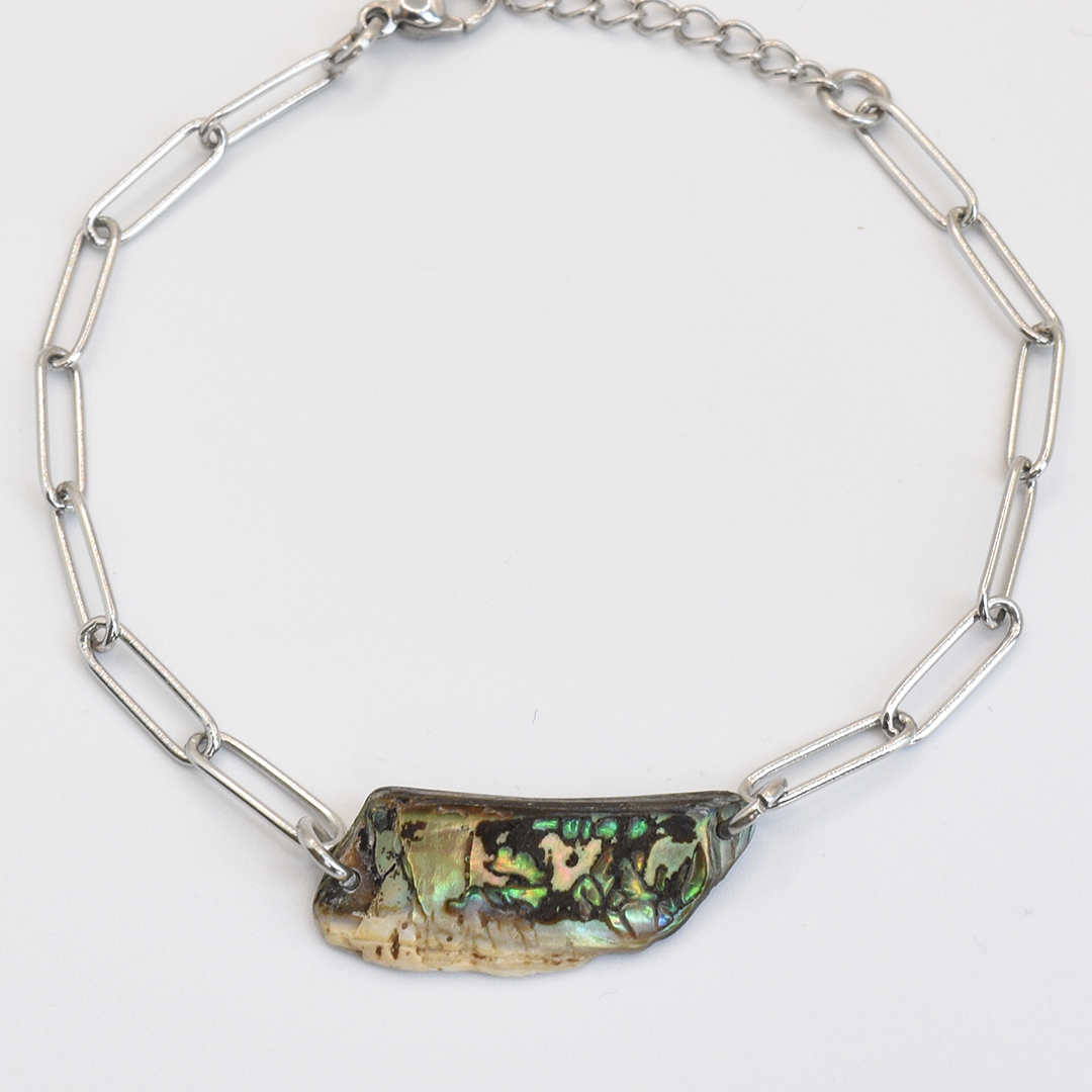 The Salty Dreamers Bracelet | Paua Shell Raumati features a handmade silver chain with elongated links and a central New Zealand paua shell pendant showing iridescent green, gold, and black hues, photographed on a white background.