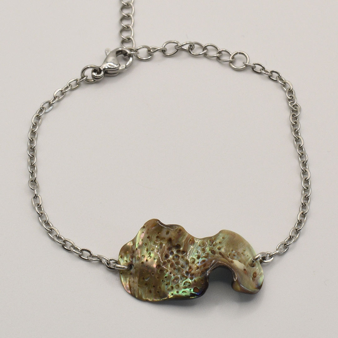 The Salty Dreamers Bracelet | Paua Shell Ra is a handmade silver chain bracelet with an irregular, iridescent abalone shell centerpiece and lobster clasp, shown on a plain light background.