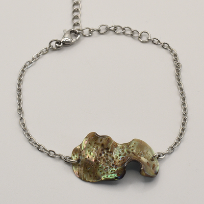 The Salty Dreamers Bracelet | Paua Shell Ra is a handmade silver chain bracelet with an irregular, iridescent abalone shell centerpiece and lobster clasp, shown on a plain light background.