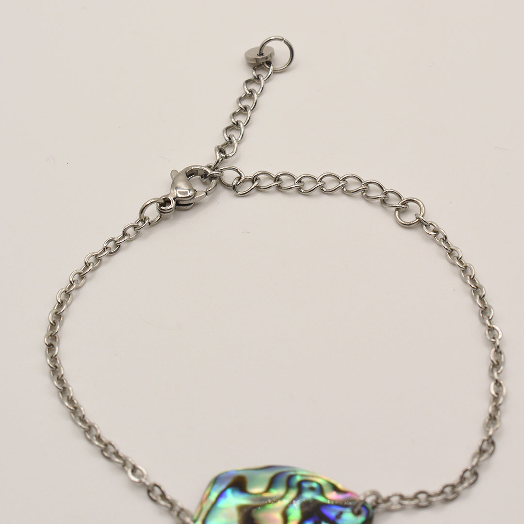 The Salty Dreamers Bracelet | Paua Shell Tumanako features a handmade silver chain with an adjustable clasp and a multicolored iridescent pāua shell charm, shown on a plain white background—a striking New Zealand jewelry piece.