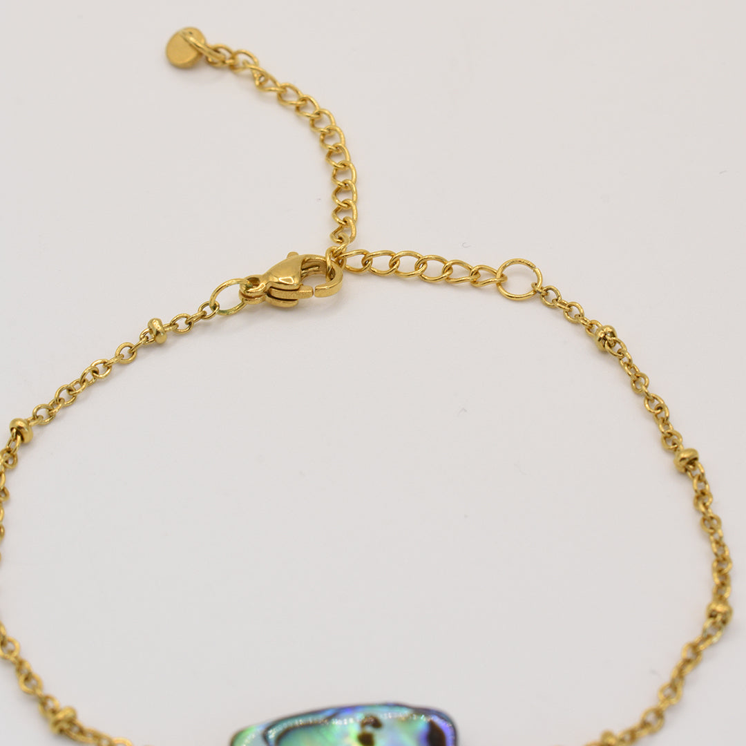 The Salty Dreamers Bracelet | Paua Shell Hau is a handmade gold chain bracelet with an adjustable clasp and small heart charm, featuring an iridescent paua shell accent. Shown against a plain white background.
