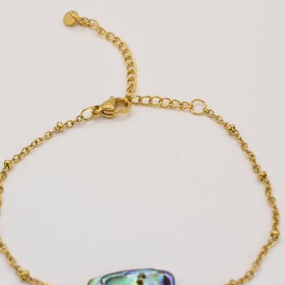 The Salty Dreamers Bracelet | Paua Shell Hau is a handmade gold chain bracelet with an adjustable clasp and small heart charm, featuring an iridescent paua shell accent. Shown against a plain white background.