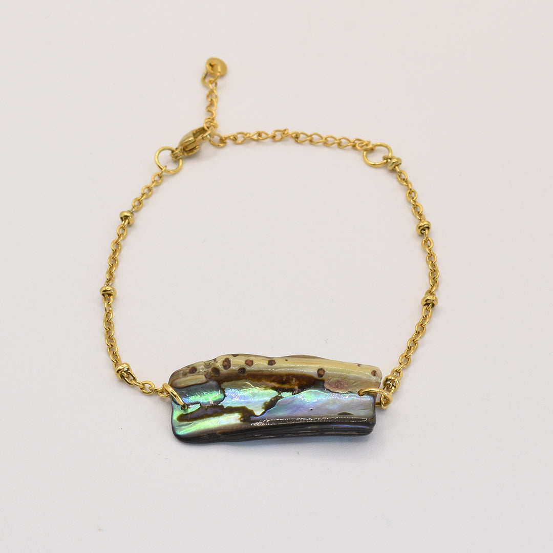 The Salty Dreamers Bracelet | Paua Shell Kaukau features an iridescent rectangular pāua shell with natural brown and green hues on a gold chain—a striking piece of New Zealand jewelry.