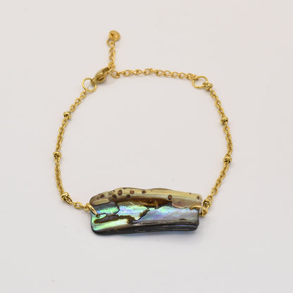 The Salty Dreamers Bracelet | Paua Shell Kaukau features an iridescent rectangular pāua shell with natural brown and green hues on a gold chain—a striking piece of New Zealand jewelry.