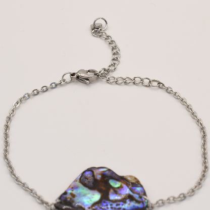 A close-up of the Salty Dreamers Bracelet | Paua Shell Ngaru, featuring a silver chain, iridescent New Zealand pāua shell centerpiece, and a lobster clasp, displayed on a light background.